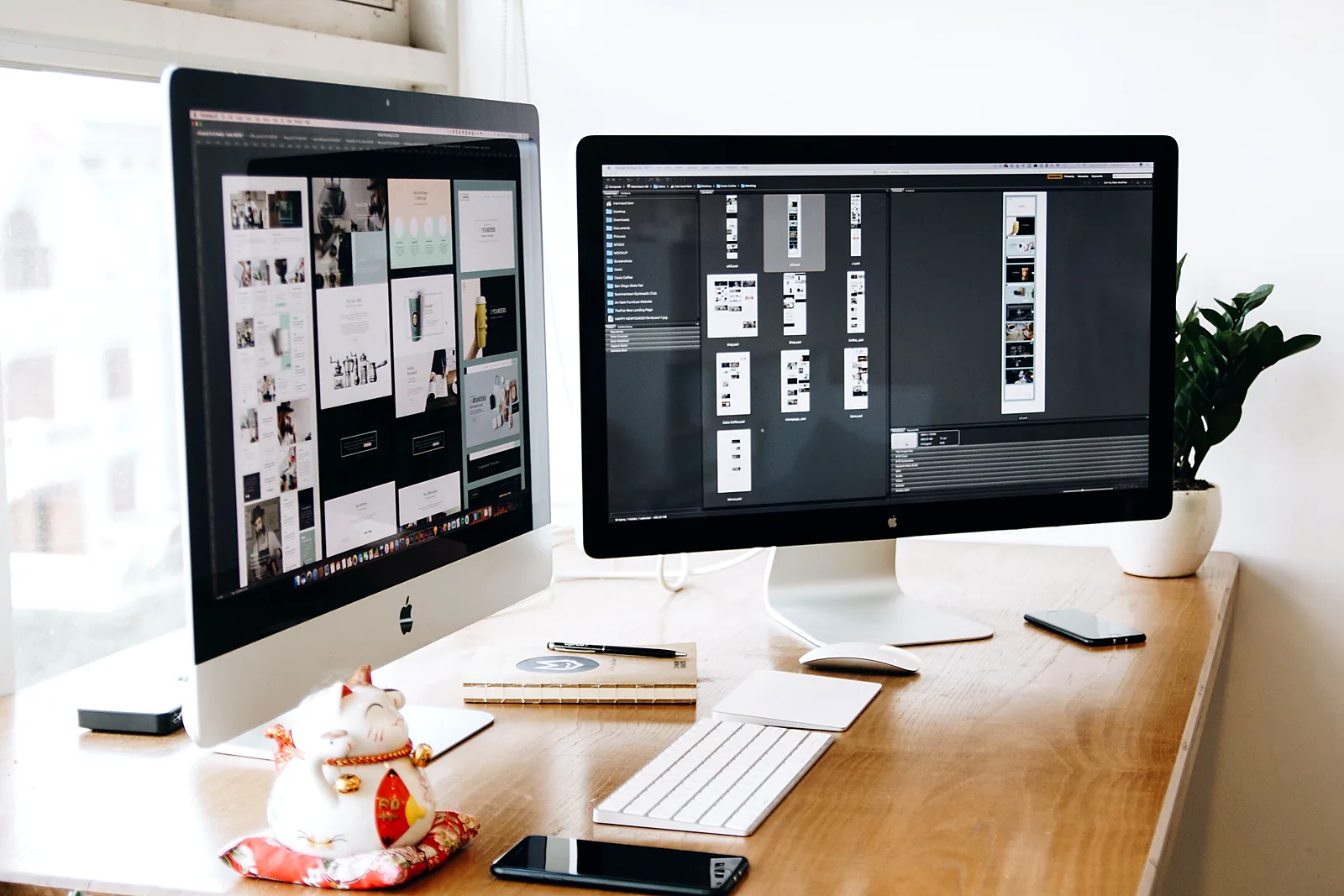 Two iMac monitors displaying website design work on a wooden desk