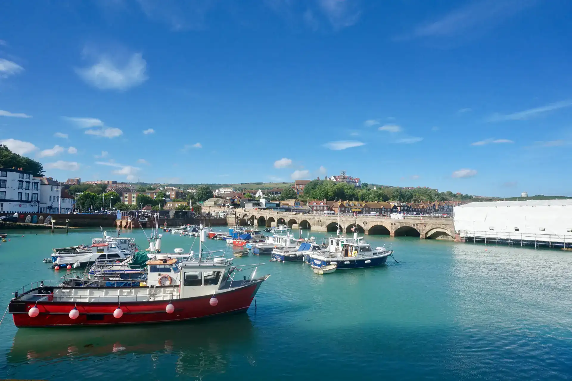 Fishing boats moored in Folkestone Harbour, with the old harbour viaduct and the town behind